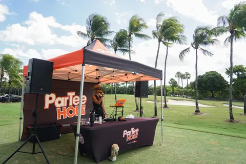An orange refreshment tent stands beside the course.